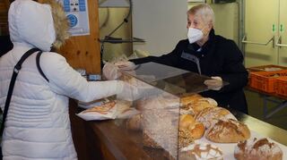 Frisches Brot gibt es im Tafelladen auch bei der wöchentlichen Ausgabe: Hellen Jilg (r.) reicht eins über die Theke.