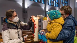 Zum Gedenken an die leidtragenden Menschen in der Ukraine: Familie Lebhardt zündet ein Friedenslicht an der Osterkerze an.
