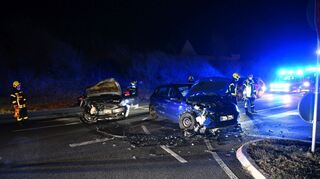 Die kaputten Fahrzeuge stehen auf der Mannheimer Landstraße, Splitter und Plastikteile liegen auf der Fahrbahn verstreut. Im Hintergrund reinigt ein Feuerwehrmann den Asphalt mit einem Besen.