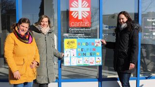 Geld für Kinder in der Not: Die Elternvertreterinnen Julia Geiß (v. l.) und Melanie Ernst vom Kindergarten St. Kilian übergeben ein von den Kindergartenkindern gestaltetes Plakat an Elisa Kranich vom Caritasverband für den Rhein-Neckar-Kreis.