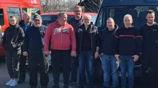 Nach dem Ausladen der Fahrzeuge im polnischen Chelm an der Grenze zur Ukraine stellen sich die Feuerwehrleute zusammen mit ihren polnischen Helfern und Dolmetschern zum Erinnerungsfoto auf.