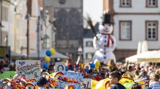 Da kommt er, der Schneemann – die Maximilianstraße ist bei bestem Frühlingswetter mit Zugteilnehmern und Zuschauern gut gefüllt.