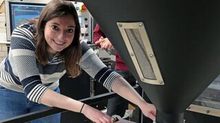 Der geröstete Kaffee wird in Metalleimer umgefüllt. Redakteurin Vanessa Schwierz schiebt die Platte nach vorne, damit der Kaffee in den Eimer fallen kann.