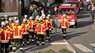 Umzug durch die Straßen: Die Wehrangehörigen laufen vom Rathaus zum neuen Rettungszentrum. Viele Zaungäste schauen dabei zu.