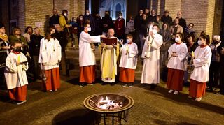 Teilweise noch mit Masken, aber endlich wieder gemeinsam: Der katholische Pfarrer Erwin Bertsch (Mitte) feiert mit seiner Gemeinde Christi Auferstehung am Osterfeuer vor der Schutzengelkirche.