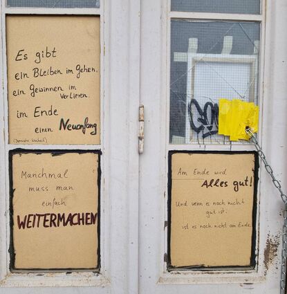 Scheiben eines zerstörten Werkstatttores wurden ausgebessert und mit mutmachenden Sprüchen versehen: „Manchmal muss man einfach weitermachen.“