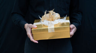 Man in black holding gold gift box