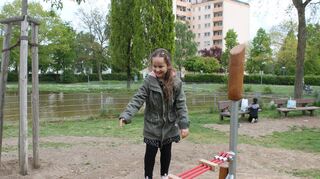 Eine junge Parkbesucherin versucht sich mit ersten Schritte auf der neuen Slackline.