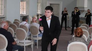 Jannik Siegler von den „Three and a half trombones“ sucht, passend zur Musik, mit einer Blume in der Hand nach der Liebe im Publikum.