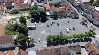Ein Blick von oben auf den Alten Messplatz, der im Zuge der Baumaßnahmen in diesem Bereich auch umgestaltet werden soll. Dabei sollen auch die Einfahrt (unten) und die Busparkplätze (links davon) verändert werden. Am linken Bildrand ist das Rothacker’sche Haus zu sehen, darüber die Freifläche, auf der früher die Spargelgenossenschaft stand.