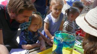 Fasziniert schauen die Kinder mit ihren Eltern zu, wie sich aus einem Unterwasser-vulkan die Lava ergießt.