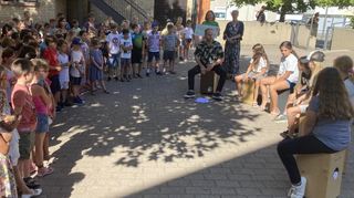 Zusammen mit allen Schülern übergibt Rektorin Juliane Groß (stehend r.) den riesigen Spendenbetrag an Annika Sparrer (l. neben ihr) von SOS-Kinderdorf. Die musikalische Umrahmung gestaltete die Cajón-AG unter der Leitung von Tobias Nessel.