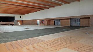 Der Aufgang zur Bühne im Hintergrund muss noch eingebaut werden, die Materialien sind da. Gleichzeitig wird der Hallenboden in einem aufwendigen Verfahren verlegt – er soll vor Verletzungen schützen.