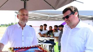 Dr. Alexander Kuhn (v. l.) von der MVV übergibt Bürgermeister Nils Drescher einen Kuchen als Dank für die gute Zusammenarbeit mit der Gemeinde.