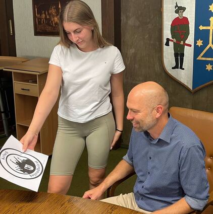 Lea Blaschko vom Jugendbeirat zeigt Bürgermeister Timo Wangler das von ihr selbst neu entworfene Logo.