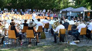 Die Bestuhlung für das Platzkonzert mitten auf der Rollschuhbahn bleibt fast komplett ungenutzt – nur hartgesottene Kulturmacher nehmen dort Platz. Das übrige Publikum hört sich die tolle Darbietung des Sinfonischen Blasorchesters unter Leitung von Tobias Nessel lieber von den schattigen Randbereichen aus an.