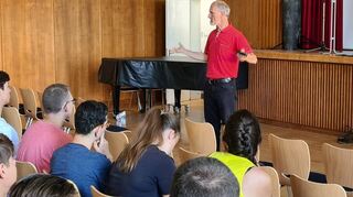 Professor Christian Stanske bei seinem Vortrag in der Aula. Im Vordergrund sind die Schülerinnen und Schüler der TGM12 am Technischen Gymnasium zu sehen.