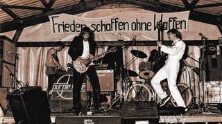 Mit Musik und politischem Motto: „Frieden schaffen ohne Waffen“ steht beim Hockenheimer Waldfestival 1981 auf dem Banner im alten Fahrerlager, vor dem die Heidelberger Band „Purple Haze“ Hardrock spielt.
