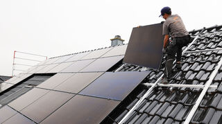 Handwerker montieren auf dem Dach eines Wohnhauses Solarmodule.
