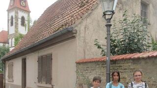 Ortserkundung: Die kleine Ferienspielgruppe des Heimat- und Kulturkreises schaut sich auch das alte Häuschen im Dietzengässel nahe der St. Kilianskirche an.