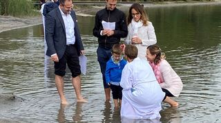 Mit hochgekrempelten Hosen und dem Gewandsaum im Wasser: Pfarrerin Katharina Garben bei einer Taufe.