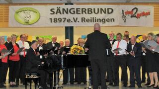 Die beiden Chöre des Sängerbundes, der Männerchor und „Sing2gether“, beim gemeinsamen Liedvortrag auf der Bühne in der Aula der Schiller-Schule.