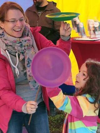 Amelia tauscht mit Mama Daniela im Mitmachzirkus Teller per Jonglage.