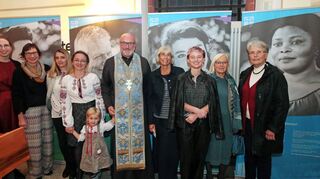 Annika Roes (v. l.), Ute Roes, Anna Dobler, Olena Molnar, Petro Bokanov, Margit Rothe, Julia Roth, Siegrid Tautz und Ann-Sofie Holland stehen vor den Ausstellungswänden. Titel der Porträtschau: „Es liegt ein Schatz in den Menschen – Vom Ankommen und Verlassen. Mut schöpfen und Mut schenken. Von Menschlichkeit und Hilfe“.