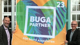 Diese Fahne hängt künftig vor dem Palais Hirsch: „BUGA 23“-Geschäftsführer Michael Schnellbach und Dr. René Pöltl zeigen sich erfreut über die Zusammenarbeit.