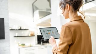 Eine Frau nutzt das Tablet, um die Smart-Home-Funktionen in ihrem Haus zu steuern. Unter anderem lässt sich die Temperatur der Heizung regeln.