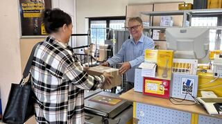 Jürgen Stang händigt einer Kundin ein Paket aus. Für ihn ist Ende Februar Schluss mit der Postfiliale in Ketsch.
