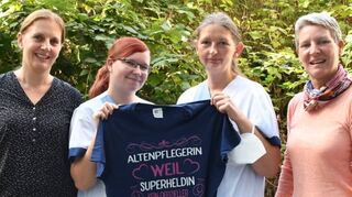 Als kleines Geschenk der Heimleitung an Kerstin D’Alton und Sarah Schulze (M.) – ein T-Shirt mit der Aufschrift: „Ich bin Altenpflegerin, weil Superheldin kein offizieller Beruf ist.