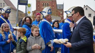 Bürgermeister Nils Drescher versucht es beim Rathaussturm mit Bestechung und verteilt leckere Berliner an die jungen Narren.