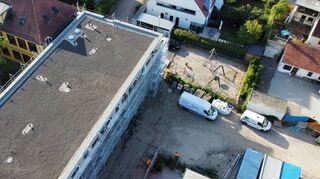 Beim Drohnen-Blick von oben sind die optimalen Möglichkeiten für die Photovoltaik-Anlage gut zu erkennen: Der Anbau (Mitte) verfügt über ein großes Flachdach, das außerdem noch begrünt wird. Oben links ist der Altbau der Alten Schule zu sehen, wo eine Sonnenstrom-Anlage ungleich aufwendiger wäre.
