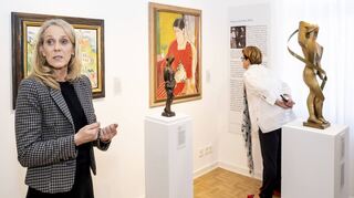 Kuratorin Maria Leitmeyer zeigt hier gerade einen Teil der aktuellen Ausstellung. Hinten von Oskar Moll das Bild „Brigitte mit rotem Kleid“, vorne von Marg Moll die Plastik „Tänzerin“.