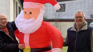 Vorbereitet auf den Weihnachtsmarkt: Kuno Mädel (l.) und Harry Schreiner halten den noch etwas labilen Nikolaus, der gerade aufgeblasen wird. An diesem Samstag soll wieder ein „pralles“ und nachhaltiges Fest für Groß und Klein stattfinden. Dabei kann sich um 17 Uhr auf den echten Nikolaus gefreut werden.