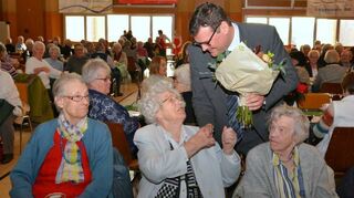 Bürgermeister Nils Drescher überreicht der ältesten anwesenden Mitbürgerin Hiltrudis Hambach einen Strauß Blumen.