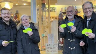 Die SPD-Ratsmitglieder (v. l.) Selcuk Gök und Gabriele Rösch, Optiker Thomas Stauffer und Dr. Ralf Göck mit ihren Glückssternen vor dem Schaufenster mit dem ersten Plakat „Ja zur Sparkasse Rohrhof“.