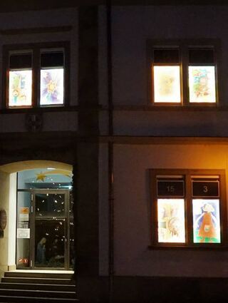 In allen Fenstern des Rathauses sind die farbenfrohen Bilder des Adventskalen- ders zu sehen.