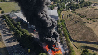 Großbrand an der Bundesstraße 39: Feuerwehrleute sorgen mit Schläuchen für die Löschwasserversorgung auf dem Gelände der Firma Delvanis in Hockenheim.