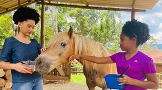 Zwei Mädchen füttern eins der Therapiepferde der neu in die Arbeit integrierten tiergestützten Therapie auf dem Land. Die Einrichtung ist eine gute Stunde von der brasilianischen Großstadt São Paulo entfernt.