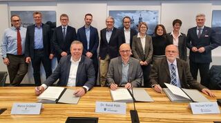 Am Tisch: Marco Grübbel, Leiter des Amtes Mannheim und Heidelberg des Landesbetriebs Vermögen und Bau Baden-Württemberg (v. l.), Schwetzingens Oberbürgermeister Dr. René Pöltl und Michael Scharf, Projektleiter der Bundesanstalt für Immobilienaufgaben (BImA), unterzeichnen den „Letter of Intent“ (Absichtserklärung) für die künftige Entwicklung der Schwetzinger Kasernenflächen. Im Hintergrund weitere Mitwirkende des Großprojekts: Norbert Baro (BImA, v.l.), Andreas Jacob (Planungsbüro FIRU mbH), Markus Rothfuß (Regierungspräsidium Karlsruhe), Ramon Eck und Wolfgang Leberecht (beide vom Amt für Stadtentwicklung Schwetzingen), Dr. Johann-Christoph Woltag (Land), Susanne Dübon (BImA), Yesim Özcelik (BImA), Martina Block (BImA) und Schwetzingens Bürgermeister Matthias Steffan.