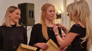 Sabrina Cass (l.) und Sarah Erles werden als Geschäftsführerinnen des Fördervereins der Schwetzinger SWR Festspiele mit dem Kulturknöchel gewürdigt, den hier First Lady Viktoria vom Club der Knöchelträger anheftet.
