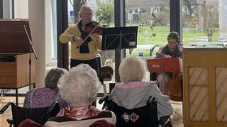 Die Bewohner des Caritas-Altenzentrums (im Vordergrund) lauschen gespannt der Musik des Hockenheimer Kunstliederensembles (im Hintergrund).