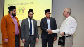 Die Spenden an Brücke übergeben (v. l.) Imam Mahfooz Ahmad Munir, Hasanat Ahmad als stellvertretender Bundesvorsitzender der AMJ und Ehsan Ranjah an Achim Schmitt vom Hilfsverein.