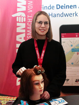 Werbung für den Friseurberuf: Hannah Reichenecker (Handwerkskammer) sorgt für Locken am Puppenkopf.