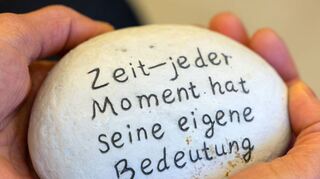 Eine Trauerbegleiterin hält einen Stein mit der Aufschrift „Zeit – jeder Moment hat seine eigene Bedeutung“. Seit der Corona-Pandemie gibt es eine steigende Nachfrage nach Angeboten zur Trauerarbeit – auch in Schwetzingen und Umgebung.