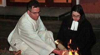 Vor dem evangelischen Gemeindezentrum entzünden der katholische Diakon Heiko Wunderling und die evangelische Pfarrerin Melanie Börnig die Kerze am Osterfeuer.