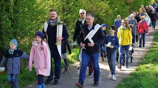 Die Gruppe geht durch Feld und Flur. Pfarrer Tobias Habicht (mit Kreuz) und Diakon Michael Barth-Rabbel schreiten vorweg.
