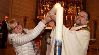 Ute Hoffmann von der evangelischen Kirchengemeinde entzündet gemeinsam mit dem katholischen Pfarrer Christian Müller die mitgebrachte Osterkerze.